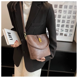 Brown vintage bucket bag with metal lock shown in a professional lifestyle setting