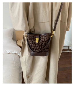 Détail du sac seau à imprimé léopard avec bordure en cuir marron et fermoir doré
