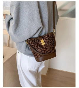 Détail du sac seau à imprimé léopard avec bordure en cuir et fermoir doré rotatif