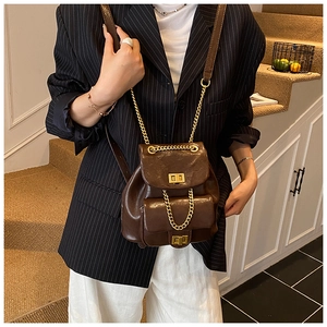 Brauner Vintage-Rucksack mit Goldkette und Drehverschluss auf schwarzem Blazer
