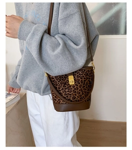 Détail d'un sac seau vintage motif léopard avec bordure en cuir et fermoir doré chic