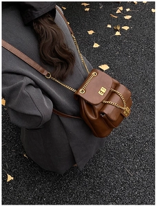 Detail eines dunkelbraunen gesteppten Rucksacks mit goldenem Drehverschluss aus PU-Leder