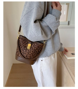 Détail du sac seau léopard avec bordure en cuir marron et fermoir métallique doré brillant