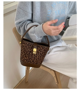 Détail du sac seau à imprimé léopard avec base en cuir marron et fermoir rotatif doré