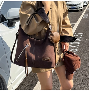 Detail of a large brown suede tote bag with fringe zippers and a matching round coin purse