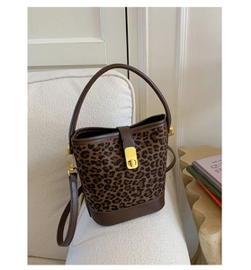 Détail d'un sac seau léopard avec fermoir doré sur un canapé minimaliste