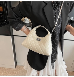 Détail du sac hobo beige matelassé avec fermoir rotatif argenté et bandoulière chaîne
