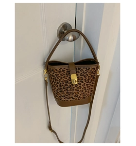 Détail du sac seau à motif léopard avec bandoulière en cuir brun et boucle dorée