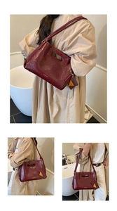 Detail of burgundy patent leather handbag with cutout handle and metal fashion tag