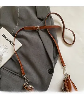 Detail of adjustable brown leather shoulder strap with silver metal buckle on a grey blazer