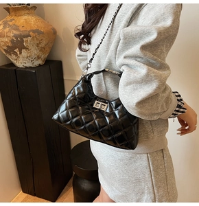 Détail du sac bandoulière en cuir noir matelassé avec fermoir rotatif et chaîne