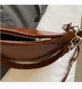 Detail view of the smooth metal zipper closure on the brown faux leather shoulder bag