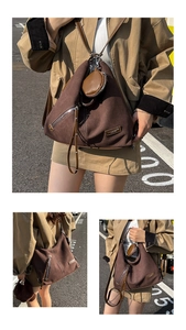 Detail of dark brown canvas hobo bag with leather straps and mini round charm pouch