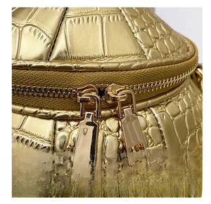 Detail view of gold crocodile embossed leather bag with smooth double metal zippers