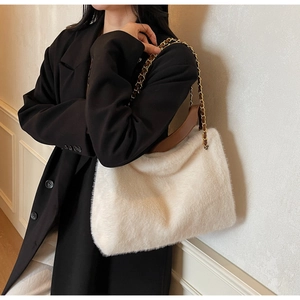 Detailed shot of white faux fur handbag featuring a gold chain and brown leather strap