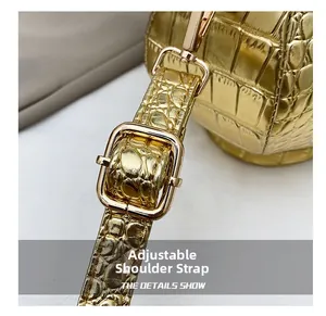 Detail of adjustable gold crocodile texture strap and metallic hardware buckle for bag
