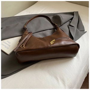 Detail view of brown matte leather hobo bag with gold zippers and hardware accents