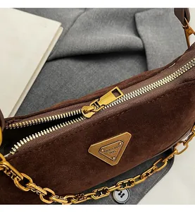 Détail du sac en daim marron avec fermeture à glissière dorée et plaque en métal doré