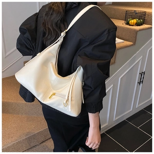 Detail of cream hobo bag showing litchi texture, side zipper, and golden hardware