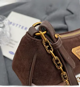 Gros plan sur la texture en daim marron foncé et la chaîne dorée haut de gamme du sac