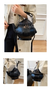 Detailed close-up of a creative teapot-shaped crossbody bag with crocodile pattern leather