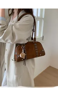 Detailed side view of brown bowling bag with suede panels and baseball glove pendant
