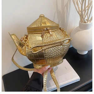 Detailed close-up of a creative teapot-shaped crossbody bag in gold crocodile texture