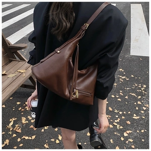 Detail of dark brown leather hobo bag with gold zipper and stylish tassel on street