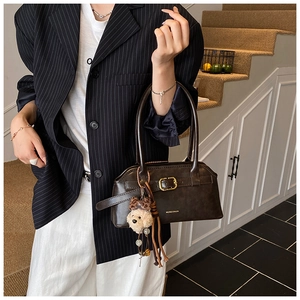 Dettaglio di borsa vintage marrone scuro con fibbia dorata e ciondolo a forma di orso