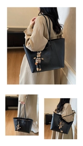 Detail of black tote bag featuring a gold logo and a cute bunny charm on the strap