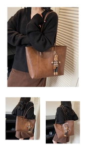 Detail of brown PU leather tote bag featuring golden logo and rabbit charm accessory