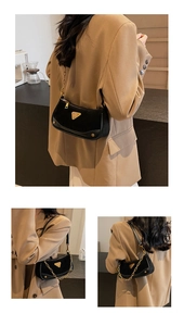 Détail du sac bandoulière noir en daim mat avec logo triangle doré et bandoulière chaîne
