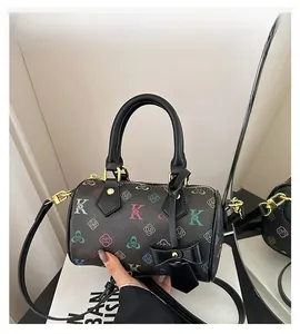Close-up of black Boston bag with colorful floral prints and gold-tone hardware detail