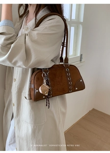 Detail of a brown retro Boston bag featuring suede texture and a plush baseball glove charm