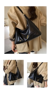 Detail view of black lychee leather tote bag with gold hardware worn by a model