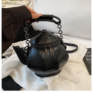 Detail of creative teapot-shaped black crossbody bag with embossed crocodile leather texture