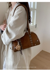 Close-up of retro brown suede Boston bag with side metal eyelets and cute charm