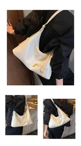 Detail view of white lychee leather texture and golden metal hardware on a hobo tote bag