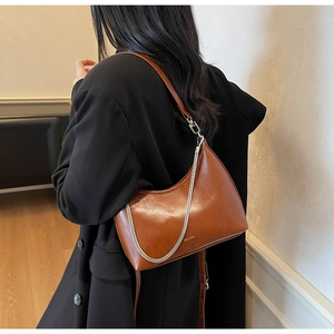 Detail of caramel crescent shoulder bag with silver chain and NO FILTER text