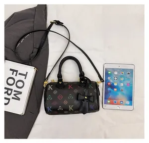 Size comparison of black Boston bag with colorful pattern next to iPad and books
