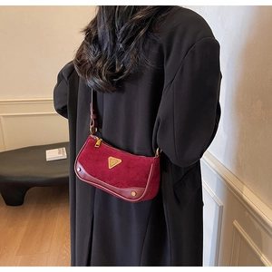 Détail du sac baguette vintage en daim bordeaux avec finitions dorées à l'épaule