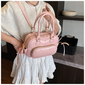 Detailed view of a pink Boston style faux leather handbag with side drawstring accents