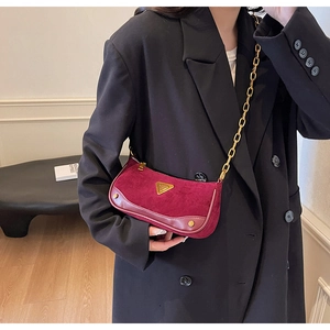Détail du sac bandoulière bordeaux givré avec chaîne dorée et logo en métal triangle