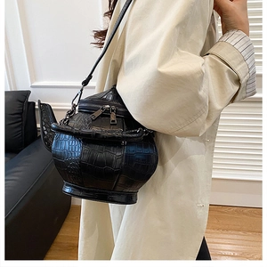 Detail of creative black teapot bag with crocodile pattern and metal zipper closure