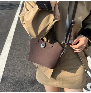 Vista street style di una borsa a secchiello in pelle marrone scuro con chiusura a scatto