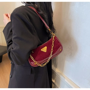 Détail du sac bandoulière bordeaux avec chaîne dorée et logo en métal sur daim chic