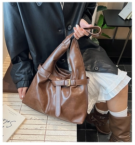 Detailed view of dark brown leather tote bag with adjustable buckle strap for commuting