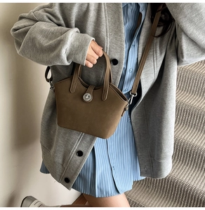 Dettaglio borsa a secchiello vintage in pelle marrone con fibbia argento e manico