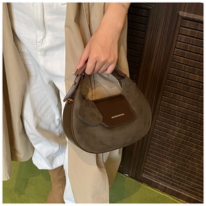 Detail of suede and leather crescent bag with brand embossing and a short top handle