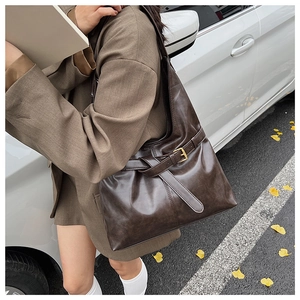 Detail of dark brown faux leather shoulder bag with vintage gold buckle and wide strap